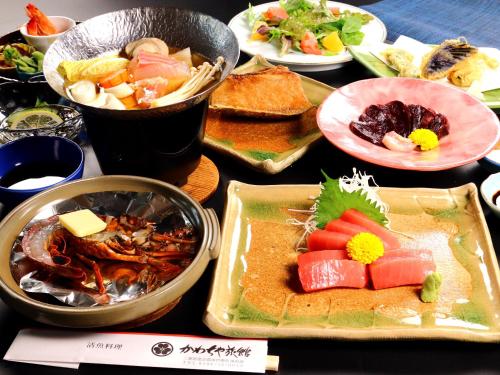 a table topped with plates of food and bowls of food at Kawachiya Ryokan in Minamiise