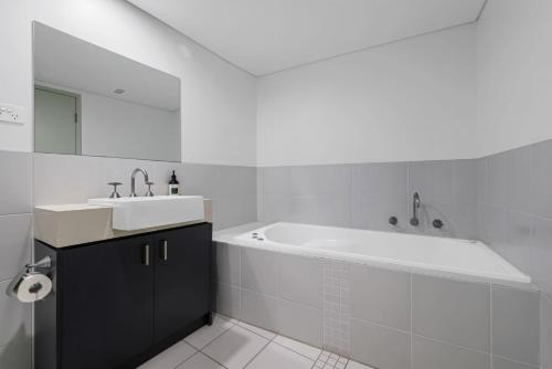 ハスキッソンにあるThe Beach Penthouse Huskissonの浴槽と洗面台のある白いバスルーム