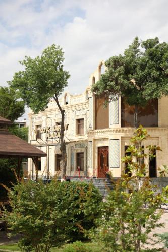 撒馬爾罕的住宿－Ko'k Saroy Plaza Hotel，前面有树木的白色大建筑