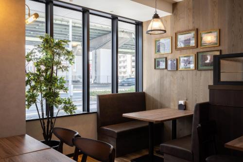 a restaurant with a table and chairs and a window at THE CELECTON Higashiosaka Nagataekimae in Higashi-osaka
