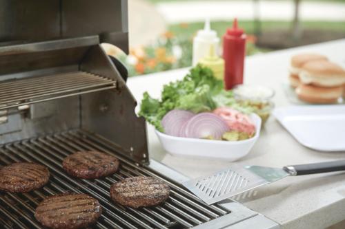 a grill with hamburgers and a salad and a plate of food at Staybridge Suites San Antonio Sea World by IHG in San Antonio