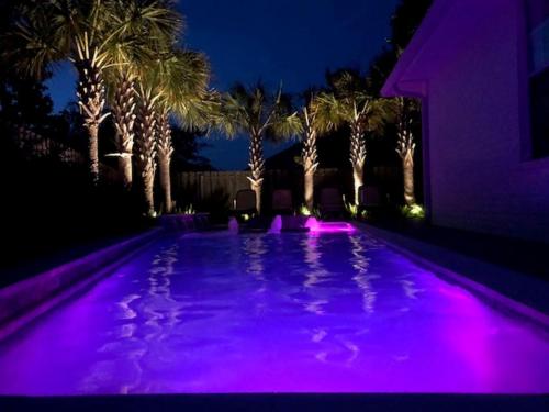 a swimming pool with purple lights in front of palm trees at Beautiful Pet Friendly Home! Tropical Pool, Optional Golf Cart & Pool Heat, Minutes to Beach in Destin