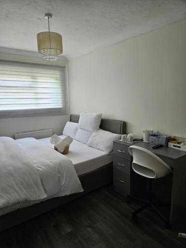 a bedroom with two beds and a desk and a window at Jays-Rooms in Pitsea