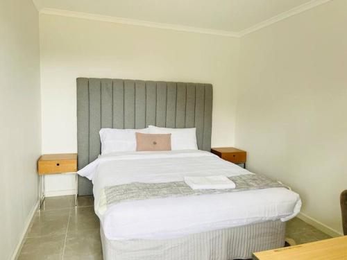 a bedroom with a large white bed with a gray headboard at Glengala D134 Glengala Best West in Ardeer