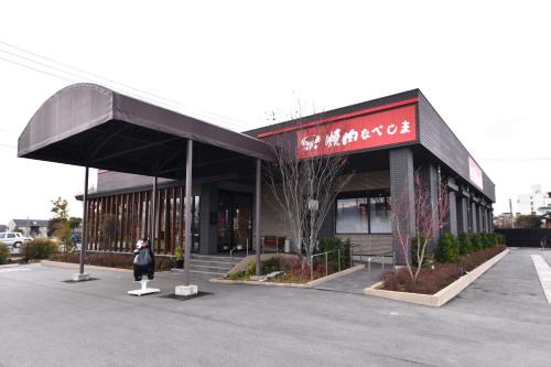a building with a woman standing outside of it at Vessel Hotel Kumamoto Airport in Ozu