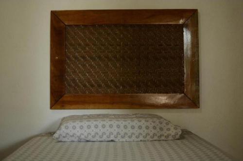 a bed with a wooden frame and a pillow on it at Espaço Sairé - 8 minutos da Praia in Alter do Chao