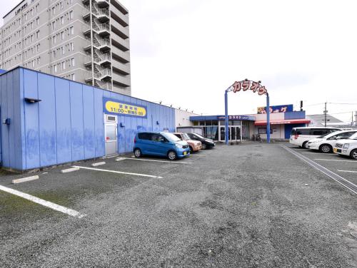 a blue car parked in a parking lot next to a building at Vessel Hotel Kumamoto Airport in Ozu