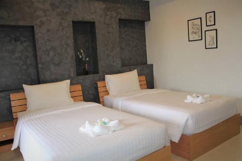 two beds in a room with white towels on them at Pilatus Apartment in Loei