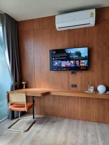 um quarto com uma secretária e uma televisão na parede em LAZYDAY IN NIMMAN em Chiang Mai