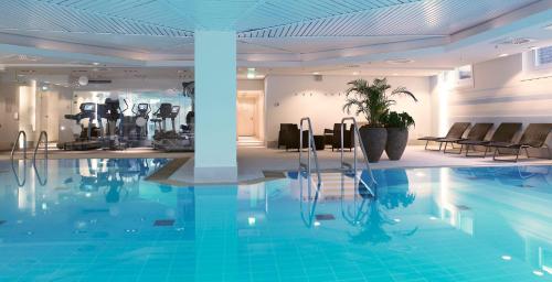 a swimming pool in a hotel with chairs and tables at Crowne Plaza Düsseldorf - Neuss by IHG in Neuss