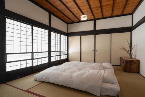 een slaapkamer met een wit bed in een kamer met ramen bij Kamogawa919 in Kamogawa