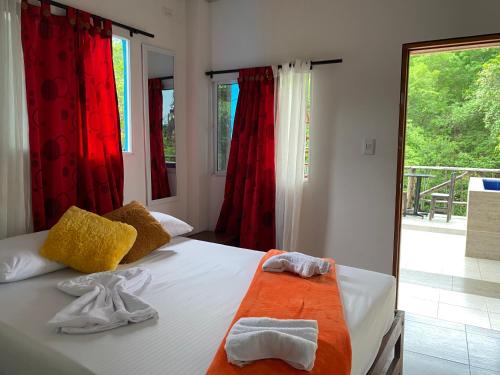 1 dormitorio con 1 cama con toallas en Eco Hostal La Perla Tayrona, en El Zaino