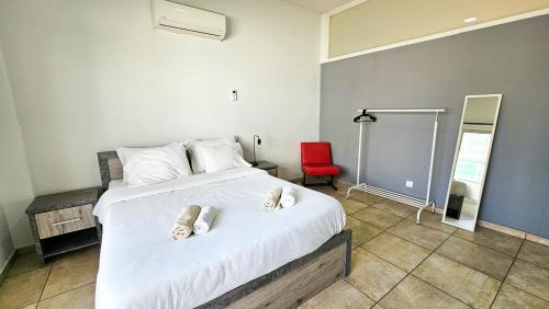 1 dormitorio con 1 cama blanca grande con silla roja en FlipFlop City Center Apartment, en Lárnaca