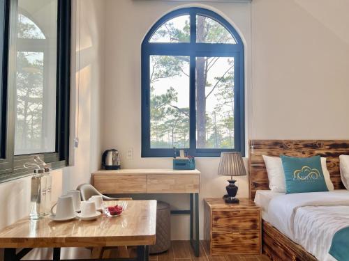 a bedroom with a bed and two windows and a table at Zephyrus Villa - Standard 1 in Kon Von Kla