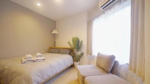 a bedroom with a bed and a chair and a window at TOKYO AKATSUKI HOTEL in Tokyo
