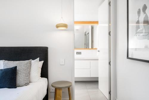 a bedroom with a bed and a stool next to a mirror at KoKo's Beach House 4 in Byron Bay