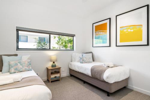 two beds in a room with two windows at KoKo's Beach House 4 in Byron Bay