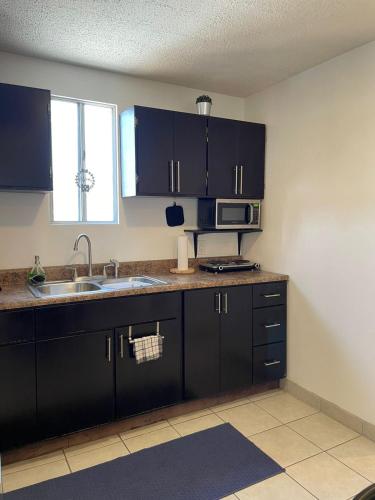 a kitchen with black cabinets and a sink and a window at Villa Angel in Tijuana