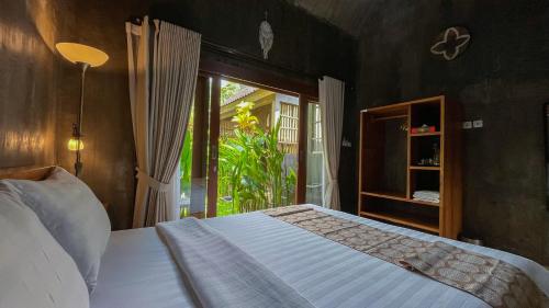 a bedroom with a bed and a large window at Elemento Homestay Badung in Bringkit