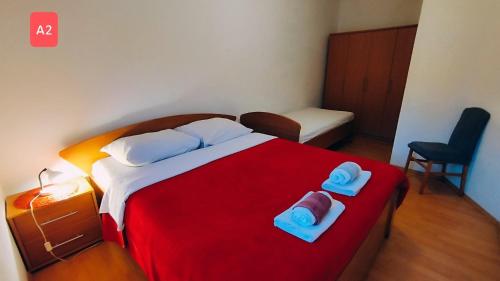 a bedroom with a red bed with two towels on it at Apartments Josef - sea view in Veli Rat