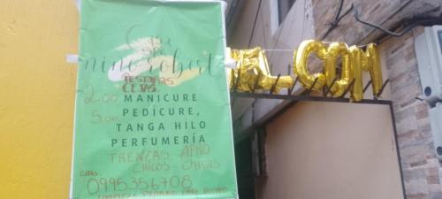 un cartello sul lato di un edificio con un cartello per un ristorante di Nails spa niño roberts a Quito
