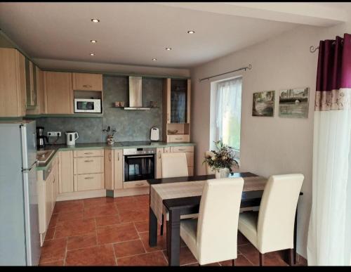 a kitchen with a wooden table and white chairs at Landleben! Bungalow Feldblick 5 Personen in Blankensee