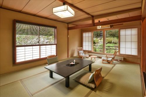 a living room with a table and chairs and windows at Uesugi no Miyu Gotenmori in Nanyo