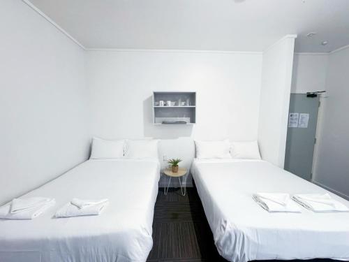 two beds in a room with white walls at 140 Ghuznee Hostel in Wellington