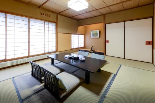 a dining room with a table and chairs and windows at Uesugi no Miyu Gotenmori in Nanyo