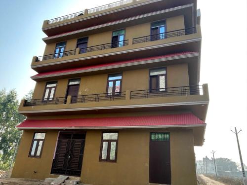 a tall building with balconies and a red roof at Hotel O AVS in Morādābād