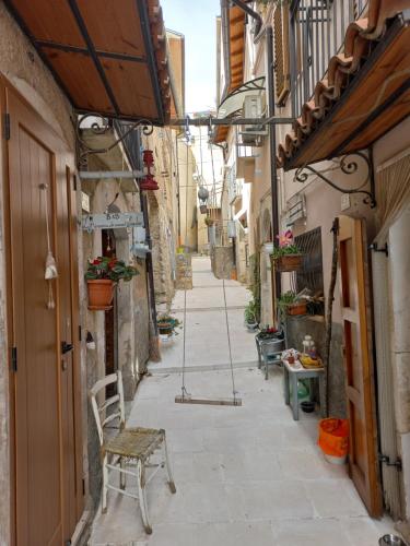 an alley with a chair and a table on a street at L'armonica di nonnoSandro in Corfinio