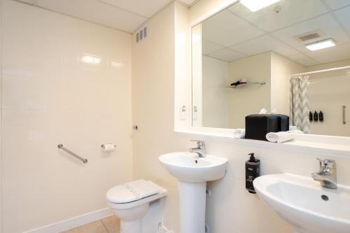 a bathroom with a sink and a toilet and a mirror at Hotel Armitage and Conference Centre in Tauranga
