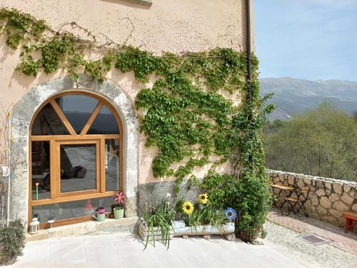 an ivy covered building with a window and flowers at L'armonica di nonnoSandro in Corfinio