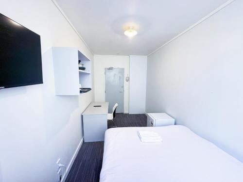 Habitación pequeña con cama y TV. en 140 Ghuznee Hostel en Wellington