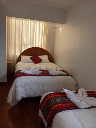 a bedroom with two beds with towels on them at Hotel TIKA AYNA Cerca a la plaza de Armas CUSCO in Cusco