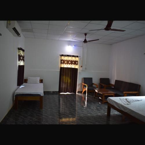 a room with two beds and chairs and a curtain at Falcon Jungle Resort in Jyoti Gaon