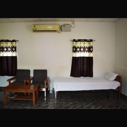 a room with two beds and a table and two chairs at Falcon Jungle Resort in Jyoti Gaon