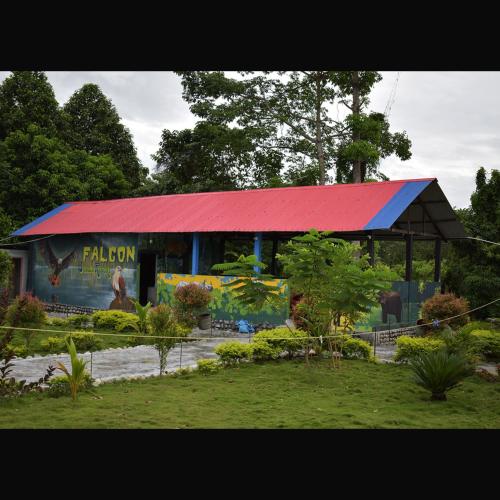 a building with a red roof in a garden at Falcon Jungle Resort in Jyoti Gaon