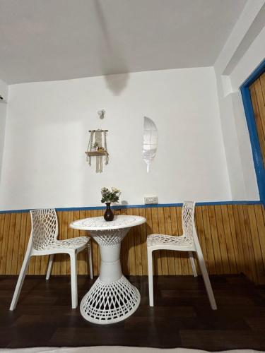 Tiny Spot Hostel في مانالي: طاولة بيضاء وكرسيين وطاولة وكراسي