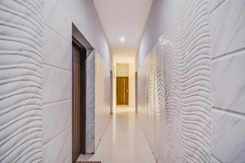 um corredor com paredes de mármore branco e uma porta em Collection O Goodwill Hotel em Jamu