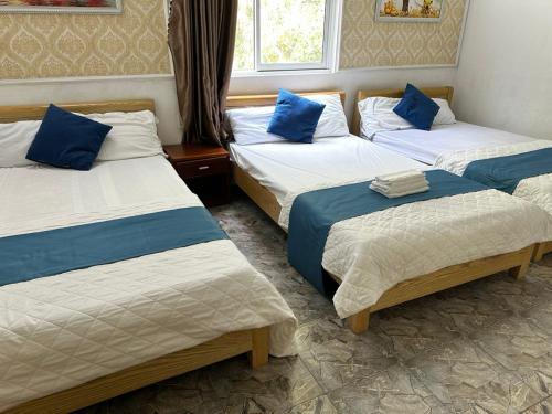 a room with three beds with blue pillows at NA NA Homestay in Cat Ba