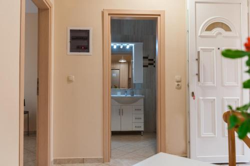 baño con puerta blanca y lavamanos en Marine Apartments Venetiko en Chios