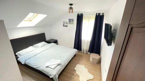 a small bedroom with a bed and a television at Cabana din Livada, Călimănești in Sălătrucel
