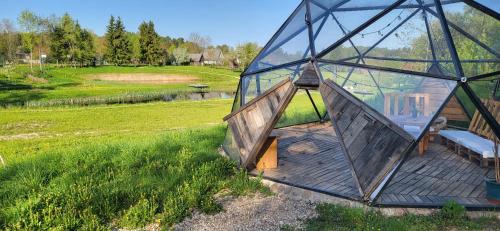 ein Glashaus mit einer Bank auf einer Holzterrasse in der Unterkunft Inovatorių slėnis/ Innovators' valley in Antalieptė