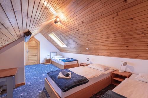 a room with two beds and a wooden ceiling at Organic Homestead Mikl in Slovenj Gradec