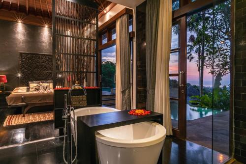 a bathroom with a tub and a large window at Villa Umah Raja in Lovina