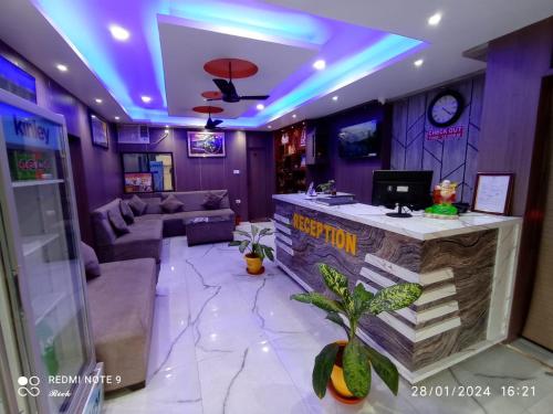 ein Wohnzimmer mit einem Sofa und einer Bar mit lila Lichtern in der Unterkunft Vaidehi Inn-A Unit of vaidehi guest house in Deoghar