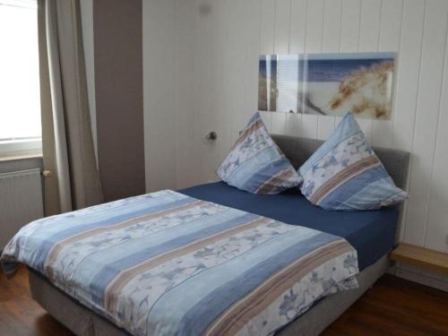 a bedroom with a bed with blue sheets and pillows at Cutter in the shiphouse in Hooksiel