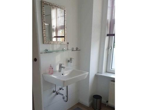 a white bathroom with a sink and a mirror at FeWo Nero Comfortable holiday residence in Niebüll
