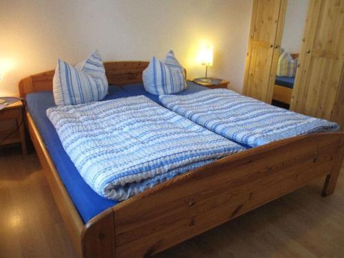 a large wooden bed with blue sheets and pillows at "Baltrum" Comfortable holiday residence in Hooksiel